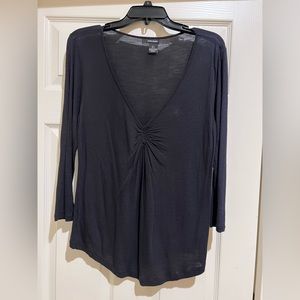 Black top with low cut neckline and gathering in the center